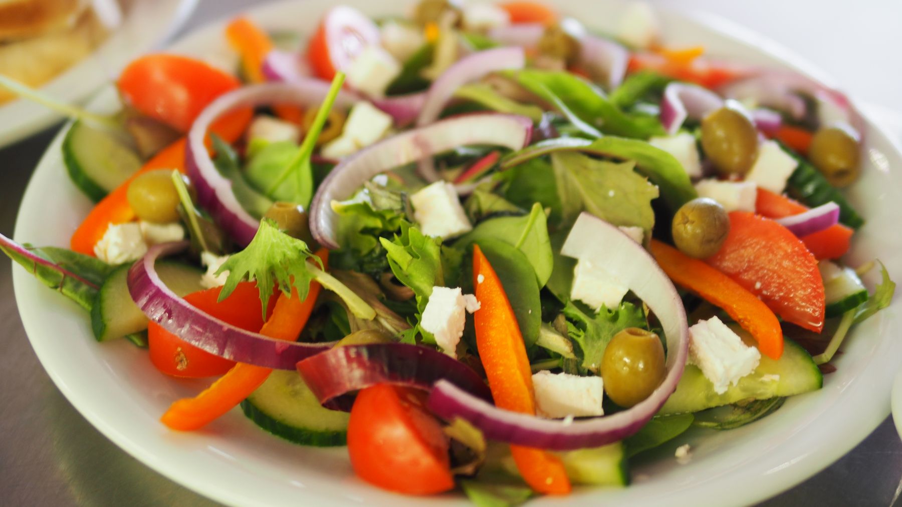 Colorful salad with peppers, olives, greens and feta; serving inspiration